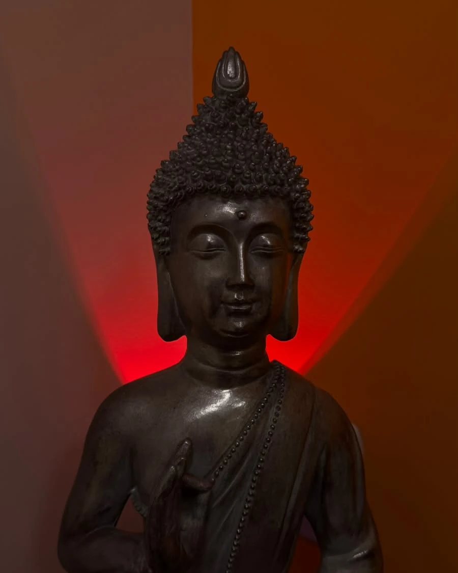 Estátua de Buda em meditação iluminada por luz vermelha suave no Ramony Wellness Center